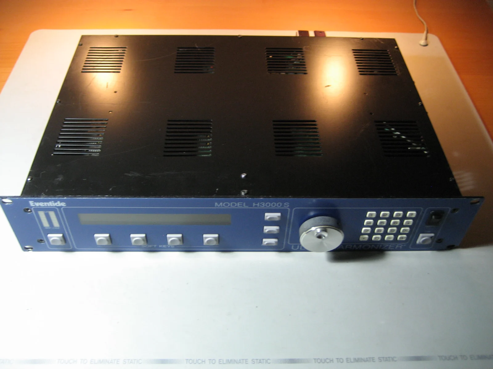 An H3000-S viewed from above at an angle. From left to right: input level meters, unlit LCD and soft keys, knob and numeric keypad.